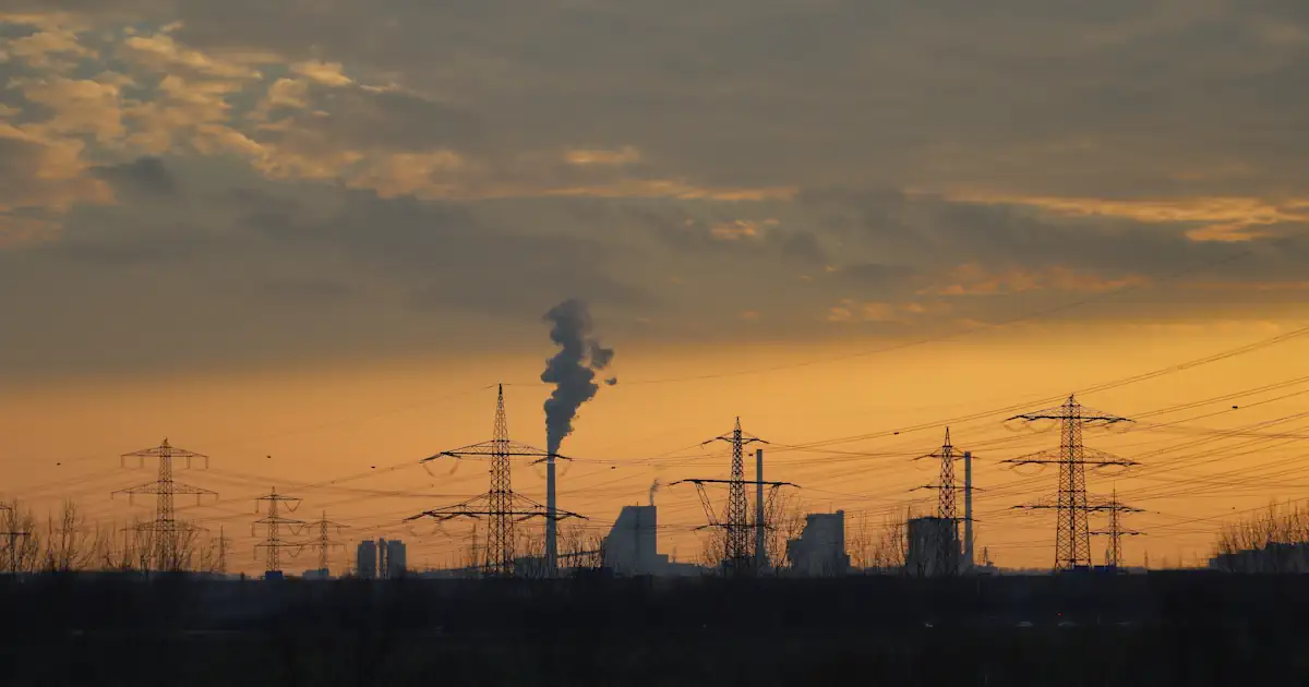 Strommasten und Kraftwerk symbolisch fuer Versorgungssicherheit
